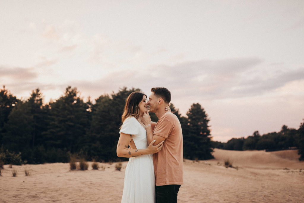 Couple kissing at an engagement session in sand dunes