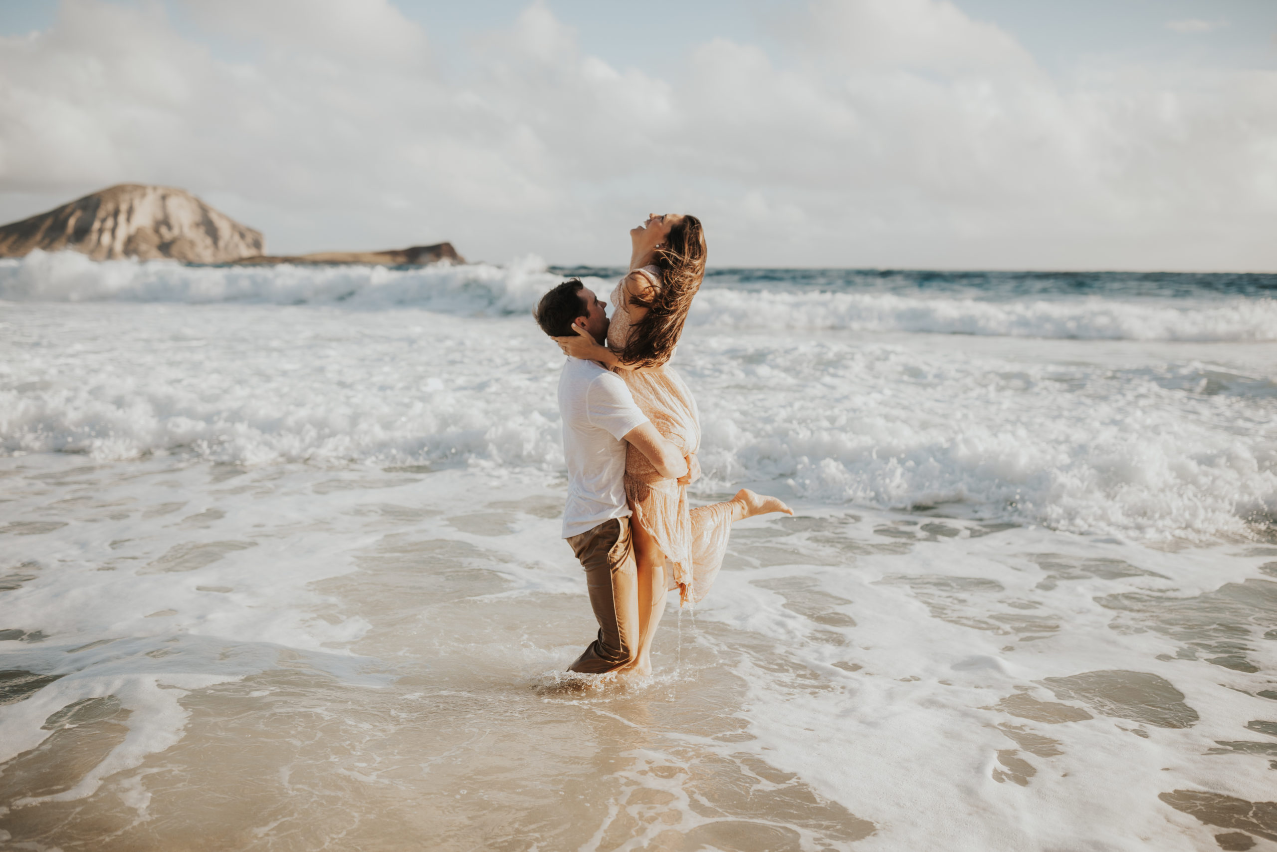 Couple hugging in water during engagement session in Hawaii