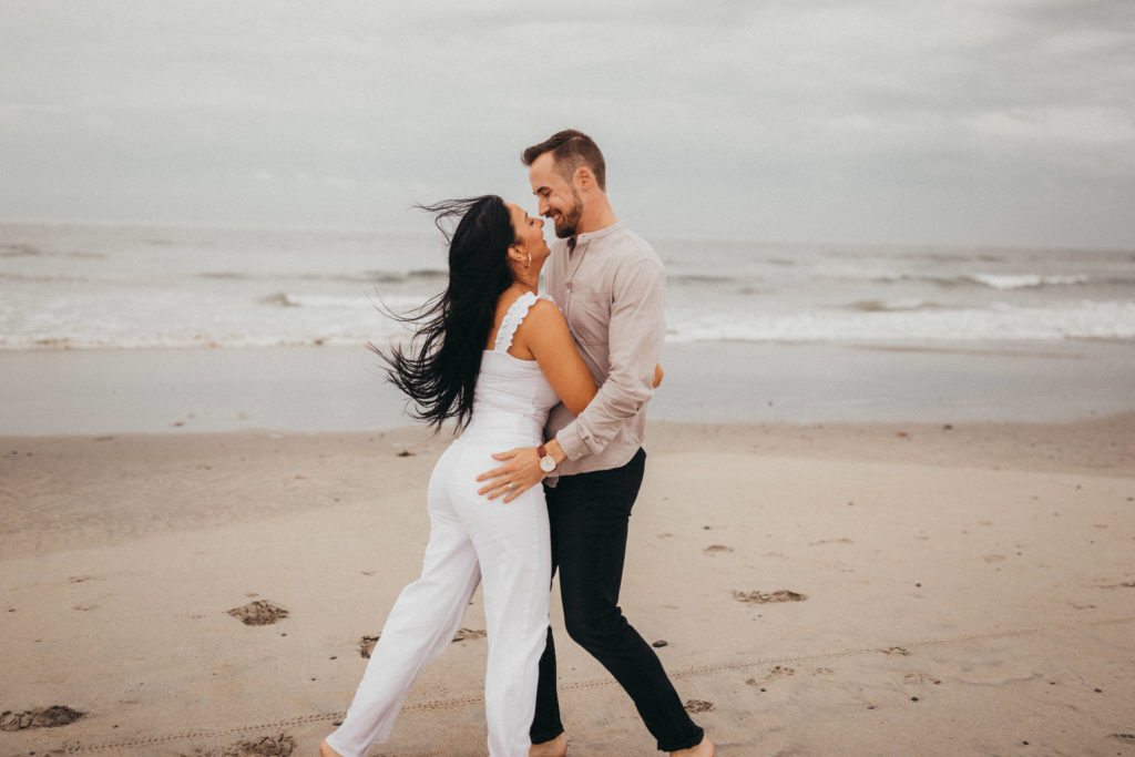Couple laughing at the beach during engagement session