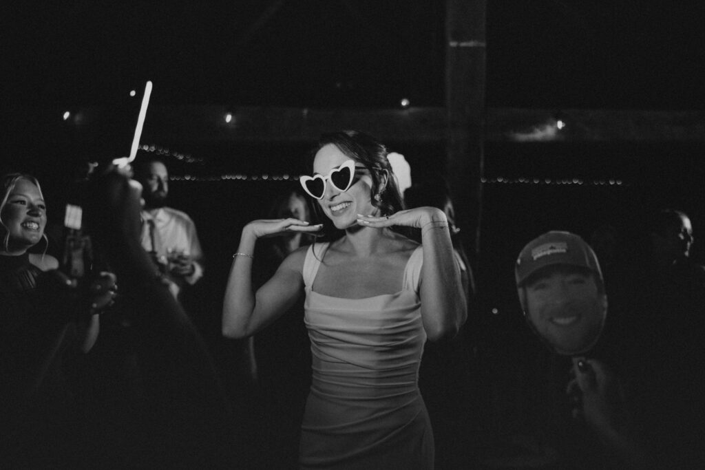 Black and white photo of bride smiling with sunglasses during wedding reception at Powder Majors Farm.