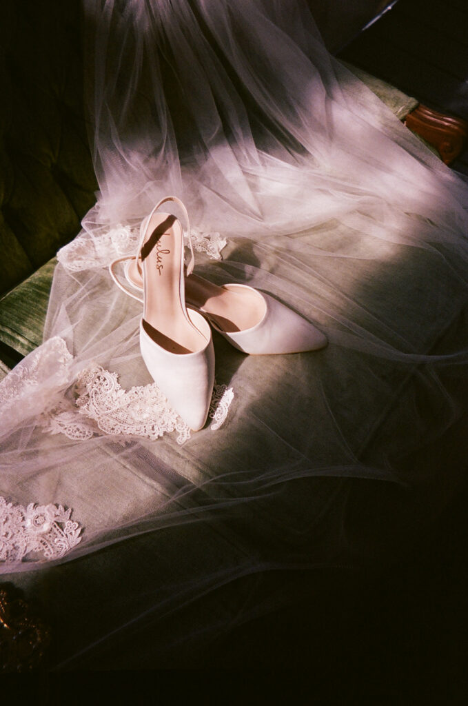 Film wedding photography detail shot of bridal shoes and veil